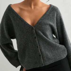 Grå kofta med v-ringning och knappar - Mysig grå kofta i stickad ullmix med v-ringning och knappar framtill. Kan bäras både med knapparna fram eller bak för olika look. Långärmad och loose passform, perfekt för lager-på-lager under höst och vinter.