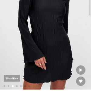 Svart ribbad kortklänning från NA-KD - Supersnygg svart ribbad klänning från NA-KD med långärmade trumpetärmar och lätt vågad kant nedtill. Kort modell med figurnära passform och rund halsringning. Perfekt att styla med boots eller sneakers för en cool look.