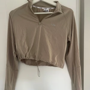 Beige croppad half zip från ICANIWILL - Snygg beige croppad tröja från ICANIWILL med half zip och dragsko i midjan. Långärmad modell i mjukt material, perfekt för träning ❤️‍🔥❤️‍🔥