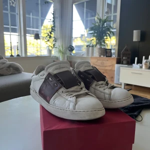 Valentino open röd - Säljes: Valentino Open Sneakers Säljer ett par klassiska Valentino Open sneakers. Skorna är i storlek EU 43  Dessa sneakers är i begagnat skick med normalt slitage. Den vita läderdelen har en del märken och sulan är sliten, vilket är vanligt efter en tids användning. Skornas överdel är i gott skick!    Storlek: EU 43 / US 10  Modell: Valentino Open Sneakers  Skick: Använda med patina och slitage  Medföljer: dustbags och andra tillbehör som ingår vid köpet. Tveka inte att fråga något