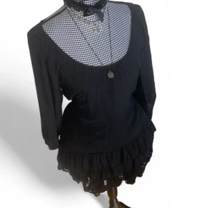 Svart kort klänning med spetsdetaljer - Supersöt svart kort klänning med långa ärmar och volangkant nertill. Klänningen har en rundad urringning och fina spetsdetaljer längst ned. Klänningen har vissa defekter såsom lösa trådar, nopprig vissa ställen och små hål som knappt syns. Ge gärna prisförslag🖤