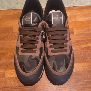 Valentino Garavani Rockrunner sneakers - Snygga Valentino Garavani Rockrunner sneakers i brunt och grönt med camouflage-mönster. Skorna har bruna mockadetaljer, svarta och gröna partier samt grov sula med mönster. Klassisk snörning och cool design som sticker ut. Skorna har aldrig blivit använda. Skriv vid frågor!!