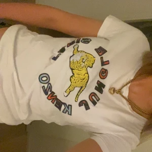 Vit Kenzo x H&M t-shirt med tiger - Vit t-shirt från Kenzo x H&M med färgglad tryckt tiger och texten 'Jungle Kenzo Paris' i coola bokstäver på bröstet. Rund hals och korta ärmar, tillverkad i mjuk bomull. Perfekt statement-plagg som köptes begagnat!