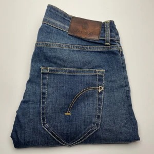 Dondup jeans  - Snygga blå jeans från Dondup med klassisk femficksdesign och cool detalj på bakfickan. Jeansen har kontrastsömmar och läderpatch med logga i midjan. Perfekta till sneakers eller boots och funkar året runt.