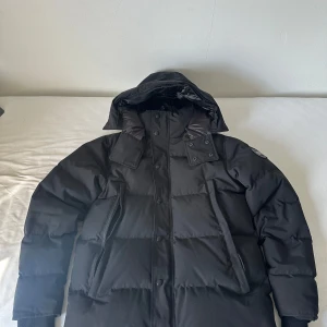 Canada Goose Wyndham black label Strl M - Säljer en svart wyndham från Canada Goose. Jackan är använd, därav priset, men har inga som helst skador eller defekter. Jackan har långa ärmar, dragkedja och knappar framtill samt två stora fickor. Insidan är fodrad med tjockt material för att hålla värmen och har märkets logga på etiketten. QR koden finns på insidan av jackan. Pris går att diskutera vid snabb affär. Hör gärna av er 🙂