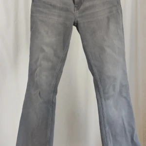 Grå bootcut jeans lager 157 - Snygga grå jeans med bootcut passform och klassisk femficksdesign. Jeansen har en något utsvängd benvidd och är tillverkade i mjukt denimtyg. Perfekta för dig som gillar en avslappnad men ändå trendig look. Storlek S short