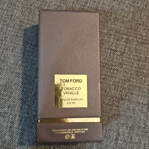 Tom Ford Tobacco Vanille 100ml EdP - Lyxig parfym från Tom Ford, Tobacco Vanille Eau de Parfum 100 ml. Flaskan är svart med en elegant guldetikett och har en unik, fyrkantig form. Kommer i en mörkbrun ask med gulddetaljer. Perfekt för dig som gillar djupa och varma dofter.
