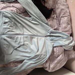 Ljusblå hoodie från Gina - Mysig ljusblå hoodie från gina med dragkedja framtill och två stora fickor. Tröjan har huva med snörning och är tillverkad i mjukt fleecematerial. Perfekt för chill dagar eller när du vill vara extra bekväm.