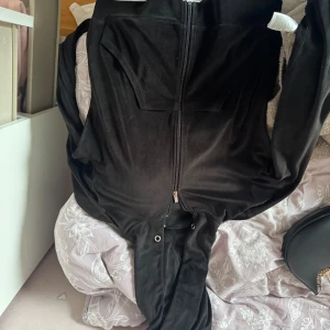 Svart jumpsuit från Gina Tricot XS - Svart jumpsuit från Gina Tricot i mjukt och skönt material, storlek XS. Hel dragkedja framtill och snygga detaljer med metallöljetter vid midjan. Perfekt för chill dagar eller när du vill vara extra comfy.