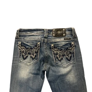Miss Me Boot Jeans - Storlek: 28  Midja rakt över: 36cm  Innerbenslängd: 77,5cm  Midjehöjd: 18,5cm  Benöppning: 21cm  Skick: Bra skick. Revorna tillhör design och går inte att se igenom.