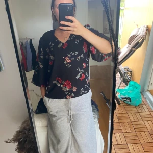 Svart blommig blus från ONLY - Säljer en svart blus från ONLY i storlek 38 med röda och beige blommor. Blusen har v-ringning och vida trekvartsärmar som ger en chill vibe. Materialet känns lätt och flowy, perfekt för vår och sommar. Snygg att styla med jeans eller kjol!