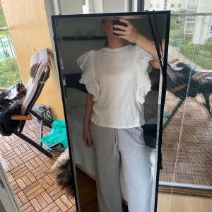 Vit blus med volangärmar - Säljer en vit blus med stora, dramatiska volangdetaljer på ärmarna. Blusen har rund hals och är tillverkad i ett lätt bomullstyg som ger en luftig känsla. Passformen är normal och modellen är kortare i midjan. Perfekt för dig som gillar statement-plagg!