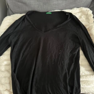 Svart v-ringad långärmad tröja  - En svart långärmad tröja i storlek L med v-ringning. Tröjan är enkel och stilren, perfekt att matcha med jeans eller kjol. Tillverkad i mjukt material som känns skönt mot huden.