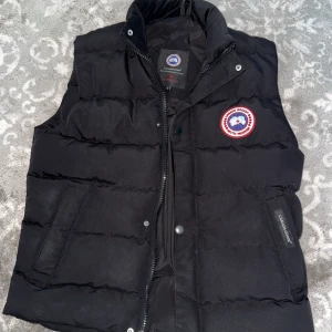 Svart Canada Goose Väst - Svart Canada Goose Väst. Använd men fortfarande i bra skick knga skador eller liknande. Vill bara sälja den för jag använder inte den. Pris kan diskuteras 