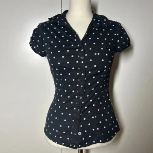 Prickig figursydd kortärmad skjorta  - Prickig tajt skjorta. Storlek 34. Från h&m, köptes för väldigt många år sedan så finns inte kvar att köpa.  Köp sker via köp nu, jag postar inom 24h. Kvar tills markerad såld