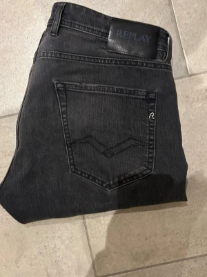 Replay Grover mörkgråa jeans straight fit - Mörkgråa Replay Grover jeans med straight fit och klassisk femficksdesign. Jeansen har diskreta sömmar, svart läderpatch med Replay-logga och är tillverkade i mjukt jeansmaterial. Perfekta för dig som gillar en clean och stilren look.