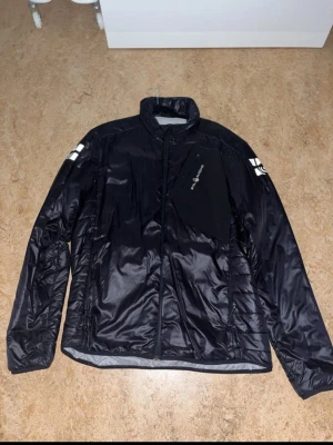 Svart Sail Racing pufferjacka herr L - Säljer en svart pufferjacka från Sail Racing i storlek L. Jackan har hög krage, dragkedja framtill och en snygg bröstficka med logga. Materialet är glansigt och består av nylon och polyester. Perfekt för dig som gillar sportig och clean stil.