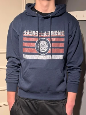 Saint Laurent Hoodie - Säljer en snygg Saint Laurent Hoodie i storlek M. Hoodien är som ny och har inga tecken på användning, modellen på bild är 185cm och väger 79,5kg.😊 hör av er vid fler frågor. MVH Karl