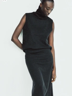 Svart ärmlös långklänning - Säljer en stilren svart polotröja med hög krage och ärmlös design. Perfekt för dig som gillar minimalistisk stil och vill ha något enkelt men snyggt. Ny med lappar kvar!