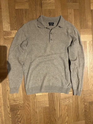 Beige pikétröja i kashmir från Massimo Dutti - Säljer en stilren beige pikétröja från Massimo Dutti i en lyxig mix av ull och kashmir. Tröjan har klassisk krage, knäppning med tre knappar och långa ärmar. Perfekt för dig som gillar en clean och tidlös look.