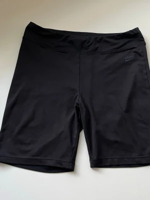 Svarta träningsshorts från Etirel - Svarta, tighta träningsshorts från Etirel i stretchigt material. De har en enkel design utan mönster och är tillverkade i polyester och elastan för maximal rörelsefrihet. Perfekta för gymmet eller löprundan.