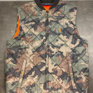 Ralph Lauren vest - Halloj, säljer en ritkigt go Ralph lauren väst i kamouflage, nästan aldrig använd och inga skador på västen. Den är kamouflage utanpå och orange innanför. Den är i storlek S. Fraktar denna säkert nerpackad så inga skador sker medans den skickas. Skickar samma dag som du köper!
