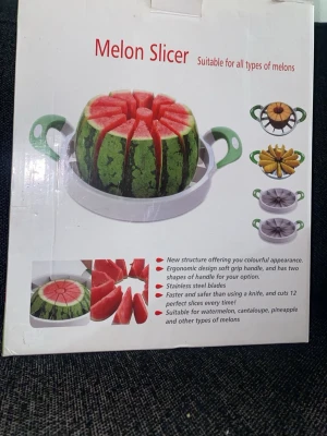 Vattenmelon slicer - Förpackningen visar en praktisk melon-slicer designad för att snabbt och säkert dela melon i jämna bitar. I centrum syns en hel vattenmelon som har skurits i perfekta klyftor med hjälp av redskapet, vilket tydligt demonstrerar dess funktion och precision. Skivorna är jämnstora och snyggt arrangerade, vilket ger ett fräscht och aptitligt intryck.