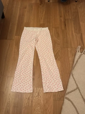 Rosa mönstrade byxor från Gina Tricot - Supersöta byxor från Gina Tricot i storlek 158/164. De är vita med rosa nallemönster över hela tyget och har en bred, ribbad midja med knappar framtill. Materialet är mjukt och bomulligt, perfekt för chill dagar hemma. Pris kan diskuteras 