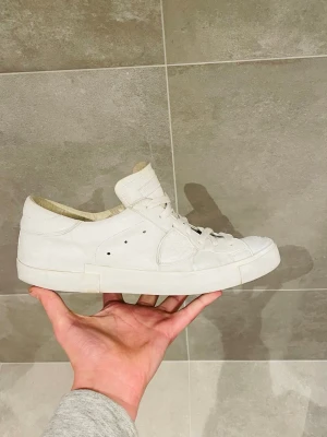 Phillippe model skor - Stilrena vita sneakers från Philippe Model Paris i skinn med klassisk låg profil och rund tå. Skorna har vita snören, diskret logga på sidan och bak, samt en platt sula. Perfekta för dig som gillar minimalistisk och clean look.