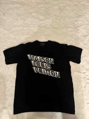 Maison lv t-shirt  - Skick:  bra skick, inga hål men 1 fläck på baksidan (se bild) Detaljer: 	•	Färg: svart 	•	Material: Stickad 	•	Passform: regular fit 	•	storlek: M (Passar medium)  Plagget kommer från rök- och djurfritt hem.  📦 Frakt: skickas samma dag om köp går igenom innan 18.00 💬 Frågor: Hör av dig om du vill ha fler bilder eller mått 🤝 Paketpris: Samfraktar gärna vid flera köp