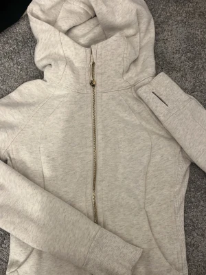 Lululemon guld scuuba zip - Jätte fin hoodie från lululemon! Den är ljusgrå med en guld zip! Funkar så fint till vardags och träning oxå! 🫶storleken motsvarar xs/s