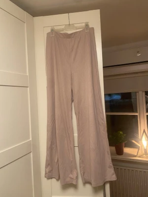 Beige ribbade byxor från H&M - Säljer ett par beige ribbade taggbyxor från H&M i storlek M. Byxorna har en relaxed fit med raka, vida ben. Materialet är mjukt och stretchigt, supersköna men passar ej längre!