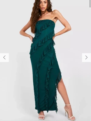 Långklänning  - Snygg mörkgrön långklänning med volanger. Axelbandslös modell med slits, från Bohoo och går inte längre att köpa. Inte använd tidigare, prislapp sitter kvar, storlek 36 !💕