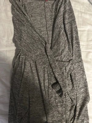 Grå tun kofta  - Mysig gråmelerad kofta. Har en avslappnad passform, perfekt att slänga över en t-shirt eller långärmad tröja. Enkel och stilren design som funkar året runt.