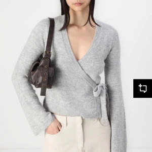 Ljusgrå omlottkofta i stickat material - Säljer nu en svart jättefin stickad omlottkofta med knyt i sidan från Gina tricot💕. Koftan har lång ärm. Perfekt för sommarkvällar eller för en väldigt fin outfit 🌸❤️skriv för egna bilder på tröjan 🥰