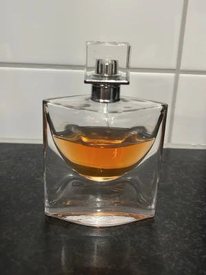 Lancome parfym  - Snygg parfym med modern, stilren flaska och orangefärgad vätska. Perfekt för dig som vill sticka ut med en exklusiv look på hyllan. Märke och doftnamn syns ej på bilderna.