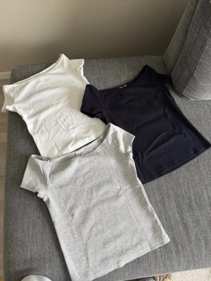 3-pack ribbade toppar i basfärger - Säljer tre ribbade toppar från H&M i vitt, marinblå och ljusgrått. Alla har korta ärmar, rund halsringning och är tillverkade i mjuk bomullsmix. Perfekta att styla med jeans eller kjol för en enkel och clean look. Tröjorna kom till användning 1 gång. 