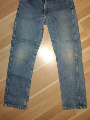 Blå raka jeans från Kaxs - Klassiska blå jeans från Kaxs med raka ben och snyggt slitna detaljer. Jeansen har normal passform, dragkedja och knapp med stjärndetalj. Tillverkade i tåligt bomullsmaterial och passar perfekt till en avslappnad stil.