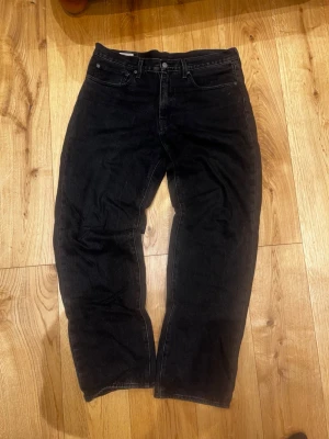 Levi's 501 svarta raka jeans - Klassiska svarta Levi's 501 jeans med baggy passform och fem fickor. Jeansen är tillverkade i slitstarkt bomullsdenim. Perfekta för dig som gillar en tidlös och clean look.