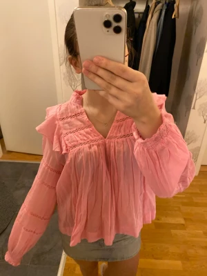 Rosa volangblus med spetsdetaljer - Söt rosa blus med volang vid axlarna och spetsdetaljer. Passar jättebra till sommaren! Jag har användt den max 3 gånger och den är köpt på neo noir's hemsida för 749kr💕Storlek 36 vilket är S💗PRIS KAN DISKUTERAS