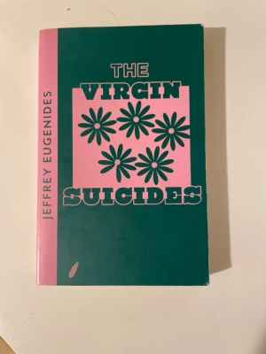 The Virgin Suicides av Eugenides - En ikonisk roman på engelska av Jeffrey Eugenides. Omslaget är grönt och rosa med blommotiv och tydlig titeltext. Boken är i pocketformat och har en modern, stilren design. Perfekt för dig som gillar gripande berättelser och klassiker.