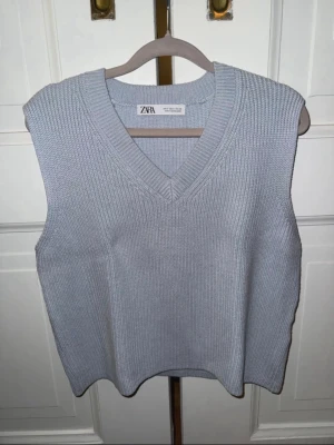 Ljusblå stickad väst från Zara - Snygg ljusblå stickad väst från Zara med bred ribbstickning och djup V-ringning. Perfekt att bära över en skjorta eller t-shirt för en trendig lager-på-lager-look. Tillverkad i mjukt material som känns bekvämt mot huden.
