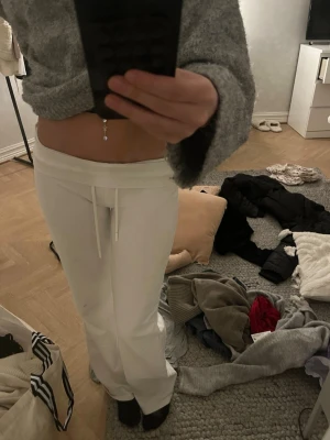 Vita mjukisbyxor med snörning Ebba  - Säljer ett par vita mjukisbyxor med låg midja och snörning i midjan. Byxorna har raka ben och är gjorda i mjukt bomullsmaterial. Perfekta för chill dagar eller när du vill vara extra bekväm.(har en fläck på benet och en liten fläck på rumpan)