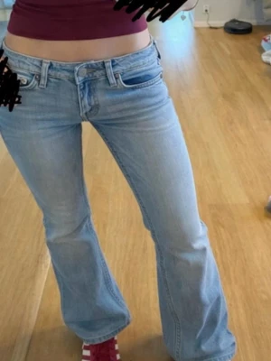 Low waist Ljusblå bootcut jeans från Weekday - Säljer ett par ljusblå bootcut jeans från Weekday, modell Nova. Jeansen har låg midja och klassisk femficksdesign. Tillverkade i bomull med en snygg tvättad look och utsvängda ben. Perfekta för dig som gillar retrovibbar och avslappnad stil.