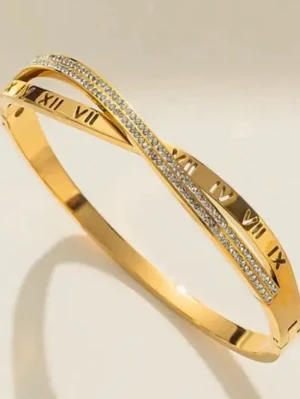 Guldarmband med romerska siffror - Snyggt guldpläterat armband med romerska siffror ingraverade runt om och en tunn rad av gnistrande stenar på ovansidan. Armbandet har en modern, stilren design och passar perfekt för dig som gillar detaljer med lite extra bling.