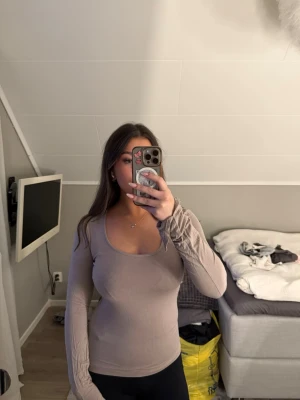 Beige långärmad topp med rund hals - Snygg beige långärmad topp med rundad urringning och figurnära passform. Perfekt att styla med jeans eller kjol för en trendig look.