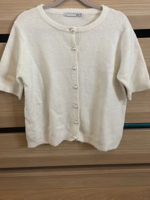 Vit kofta med pärlknappar från 157 - Supersöt vit stickad kofta från 157 med korta ärmar och pärlknappar framtill. Storleken är 140 men passar mig som oftast har storlek 152-158 eller xxs-xs. Orginalpris är 179kr🥰🥰