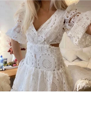 Vit spetsklänning med volang - Supersöt vit klänning i spets med v-ringning och volangdetaljer. Klänningen har korta ärmar, omlott över bysten och öppen rygg. Perfekt för sommarens alla tillfällen. Väldigt populär student klänning! Först till kvarn!🙌