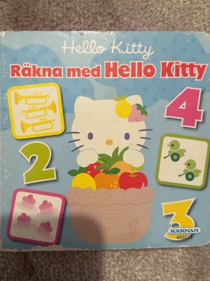 Räkna med Hello Kitty bok - En färgglad och söt barnbok med Hello Kitty-tema där man får lära sig siffror och färger. Boken har hårda pärmar, blå bakgrund och illustrationer av Hello Kitty samt olika objekt och siffror. Perfekt för yngre barn som vill lära sig räkna tillsammans med en populär karaktär.