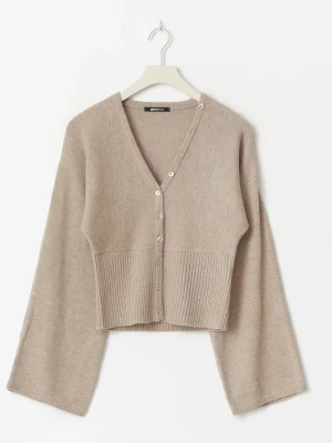 Beige cropped kofta från Gina Tricot - Trendig beige kofta från Gina Tricot med croppad passform och vida ärmar. Koftan har V-ringning, ribbstickad nederkant och knäppning med silvriga knappar. Perfekt att styla över ett linne eller t-shirt för en chill look.